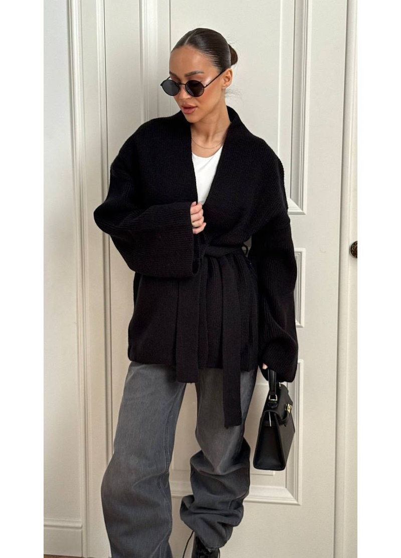 Женщина-модель на показе моды одета в  кардиган: